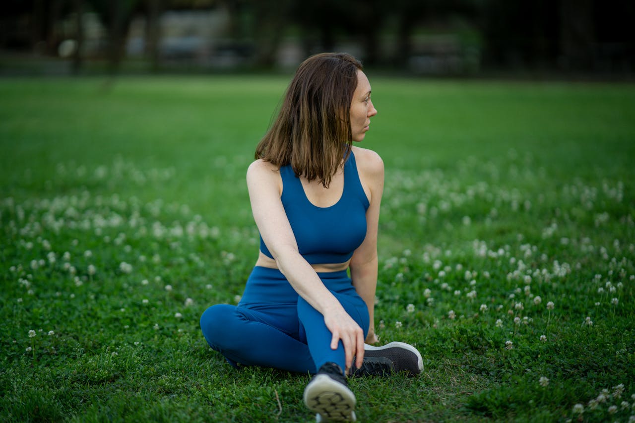 Woman practicing yoga outdoors in a serene green park setting.